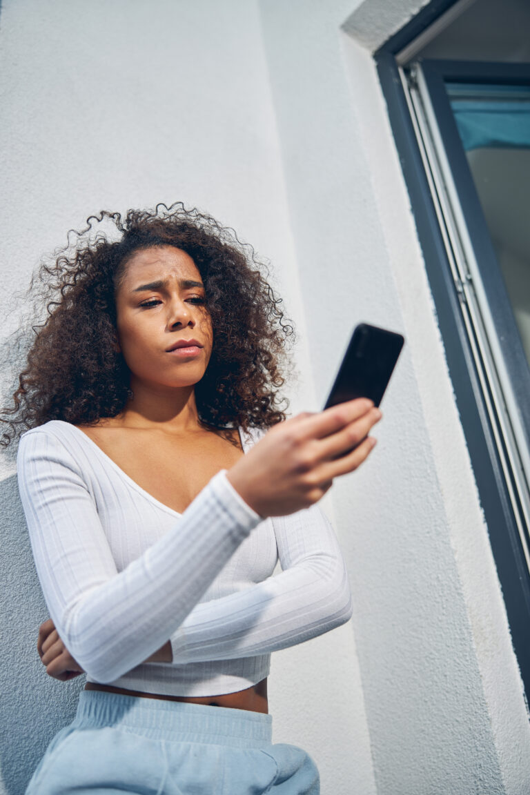 Personne regardant tristement l'écran de son smartphone affichant une conversation restée sans réponse.