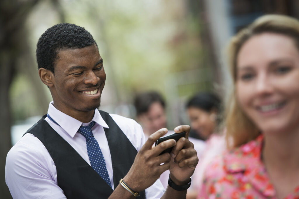 Personne souriant doucement, l'air soulagé et apaisé, regardant son téléphone dans un environnement lumineux.