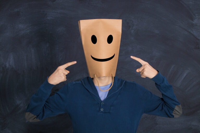 Personne affichant un grand sourire forcé lors d'un repas pour masquer sa détresse psychologique aux yeux des autres.