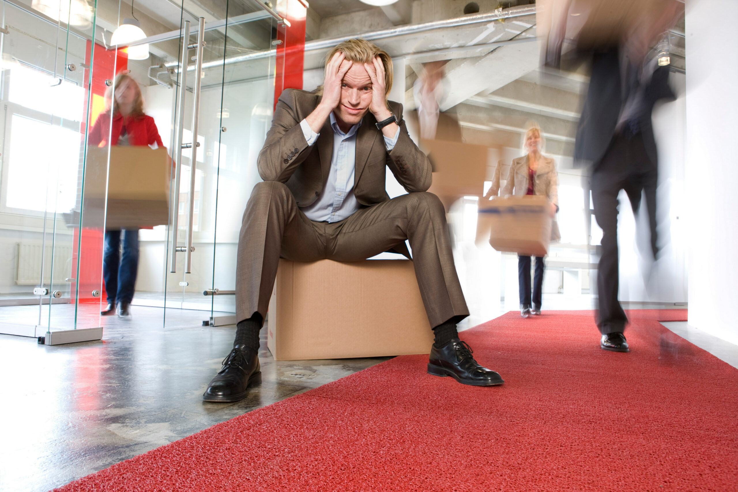 Personne au milieu d'un groupe ou d'un open-space, l'air figé et légèrement déconnecté, contrastant avec l'agitation normale autour d'elle.