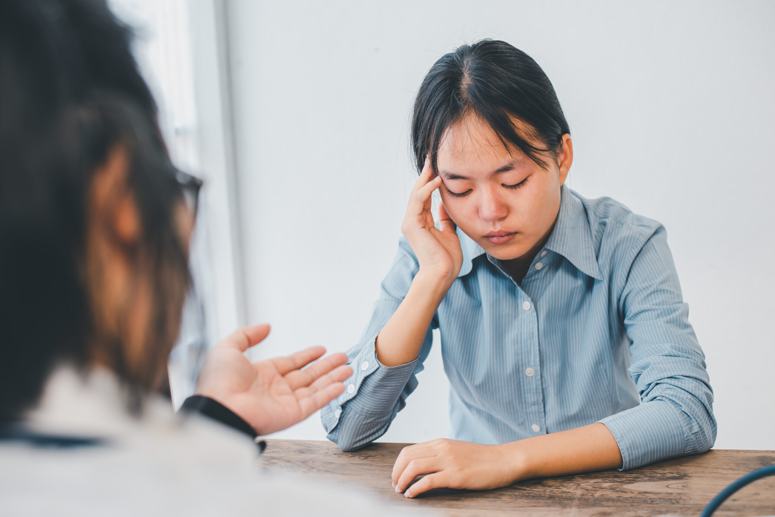 Personne angoissée hésitant avec son téléphone en main devant l'entrée floue d'un cabinet médical.