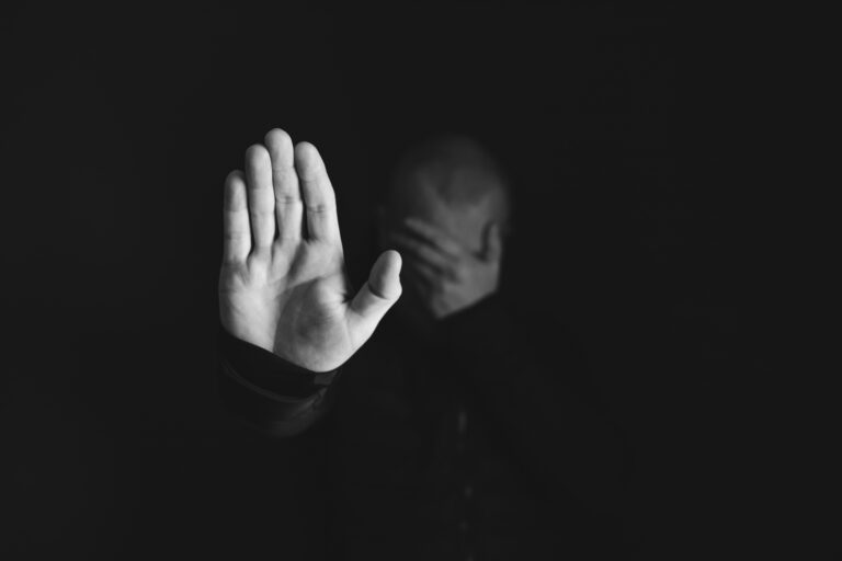 Personne dans l'ombre, le visage caché dans ses mains, illustrant la difficulté de porter un secret seul.